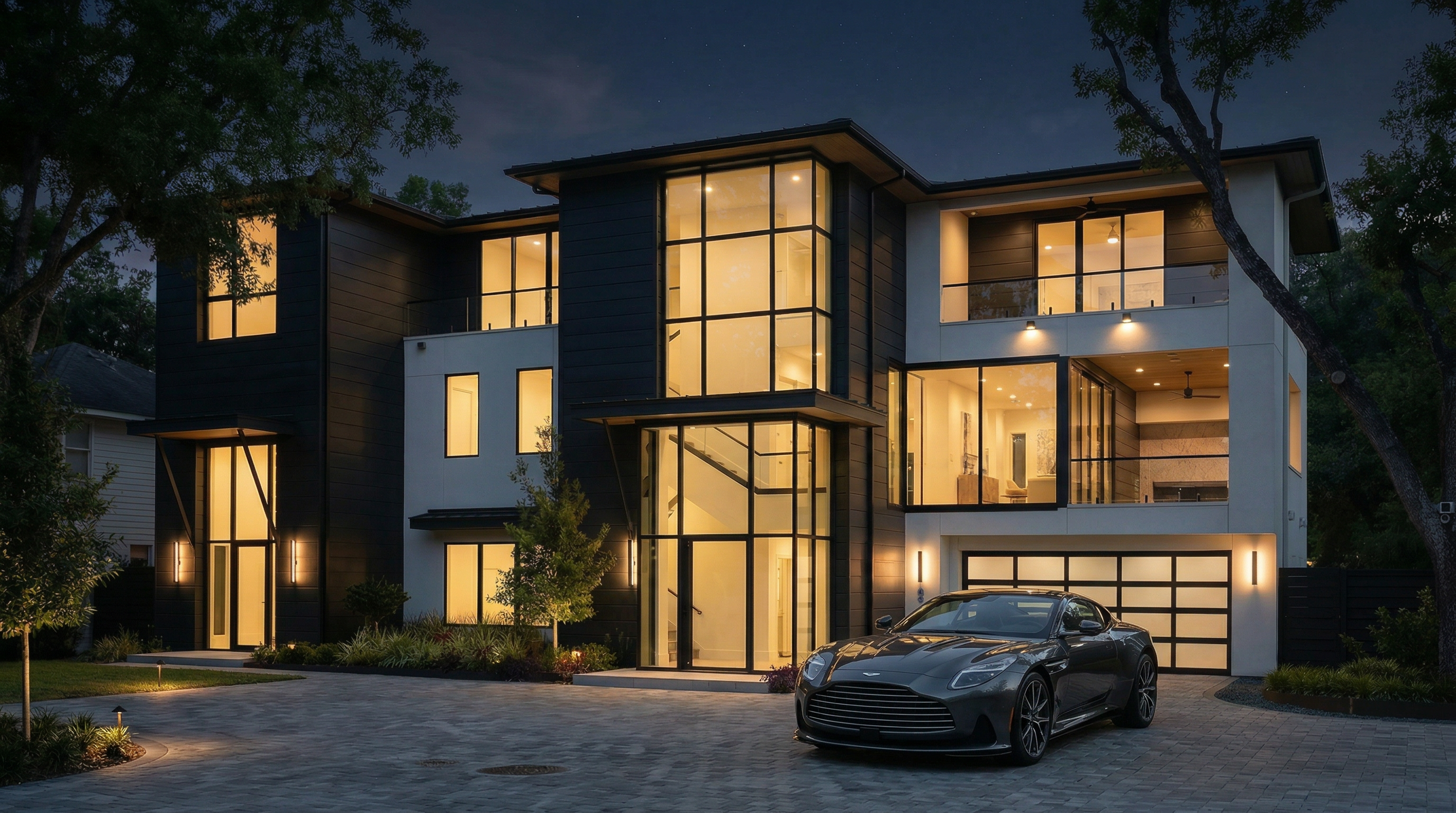 This stunning contemporary residence makes a bold statement with its striking contrast between dark paneling and crisp, white architectural lines. The home features expansive floor-to-ceiling glass windows, an integrated two-car garage, and warm ambient exterior lighting that highlights its modern aesthetic. Its clean geometry and tiered structure create a sophisticated, high-end curb appeal that balances privacy with an open, airy design.