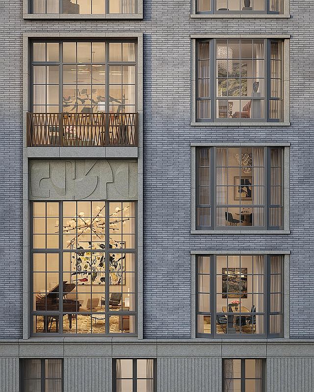 This architectural exterior view showcases a sophisticated multi-story building facade constructed from grey brick with stone accents. The composition features a mix of large, multi-pane windows, a decorative stone relief panel, and a balcony with a geometric metal railing. The perspective is a straight-on, eye-level shot that highlights the refined, urban aesthetic and the intricate detailing of the building's exterior design.