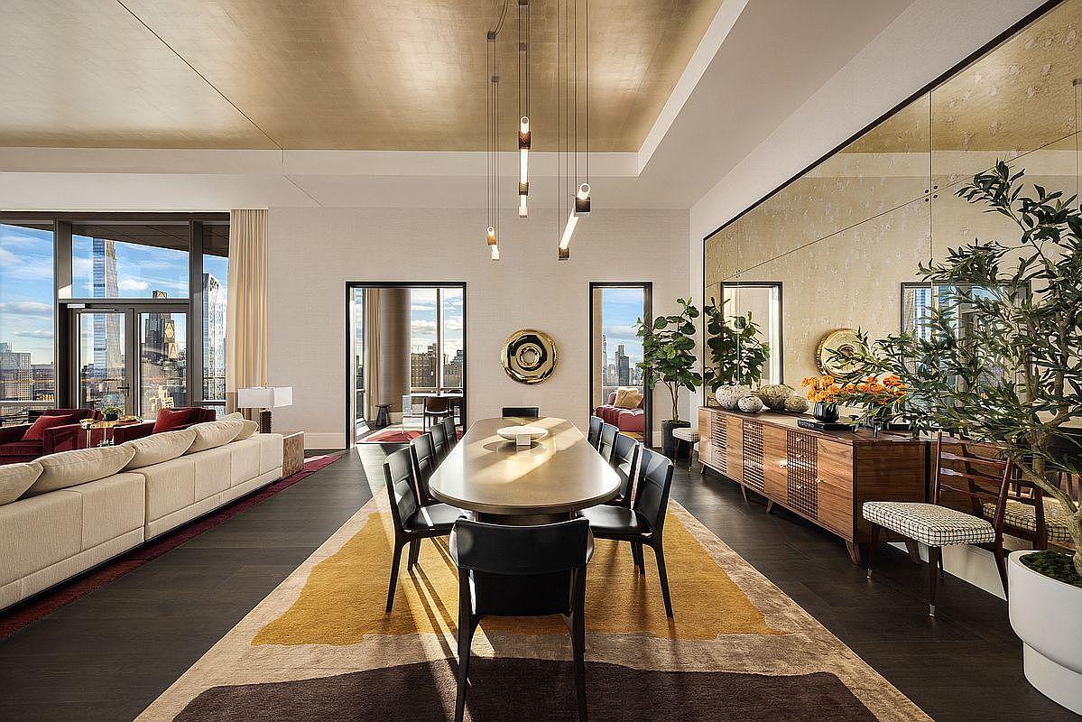 This sophisticated dining room features a long, oval-shaped table surrounded by sleek black chairs, set beneath a striking arrangement of modern pendant lights. The room is anchored by a large, abstract-patterned area rug and a warm, gold-leaf ceiling that adds a touch of opulence. A wooden sideboard sits against a mirrored wall, reflecting the space and enhancing the airy, high-end atmosphere, while floor-to-ceiling windows offer expansive city views.