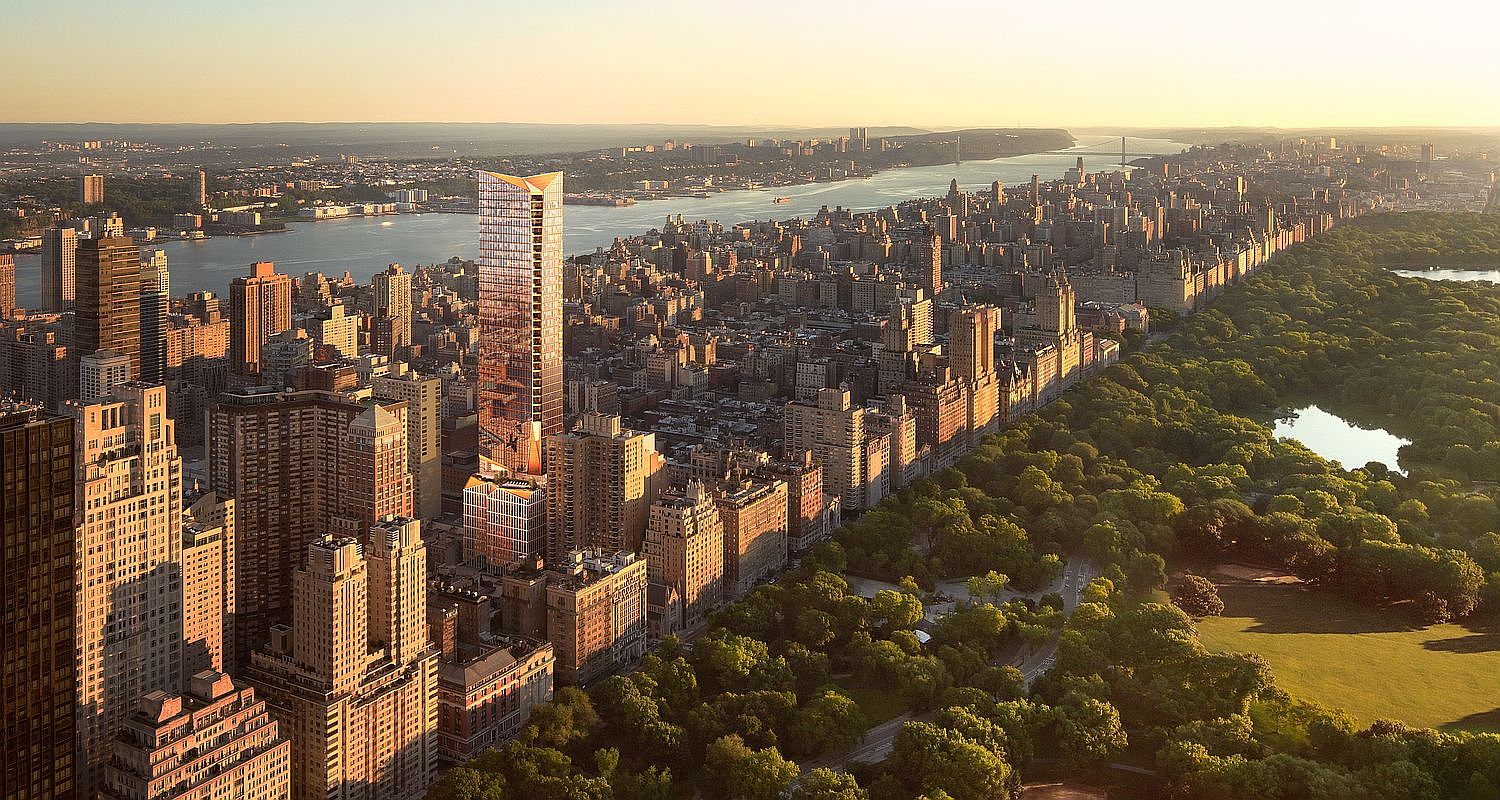 This high-angle aerial perspective captures a prominent, modern skyscraper rising above the dense urban fabric of Manhattan, positioned prominently near Central Park. The golden hour lighting casts a warm glow over the city's architecture, highlighting the contrast between the historic residential buildings and the sleek, reflective glass facade of the new development. The expansive view stretches toward the Hudson River, emphasizing the building's prime location and commanding presence in the iconic New York City skyline.