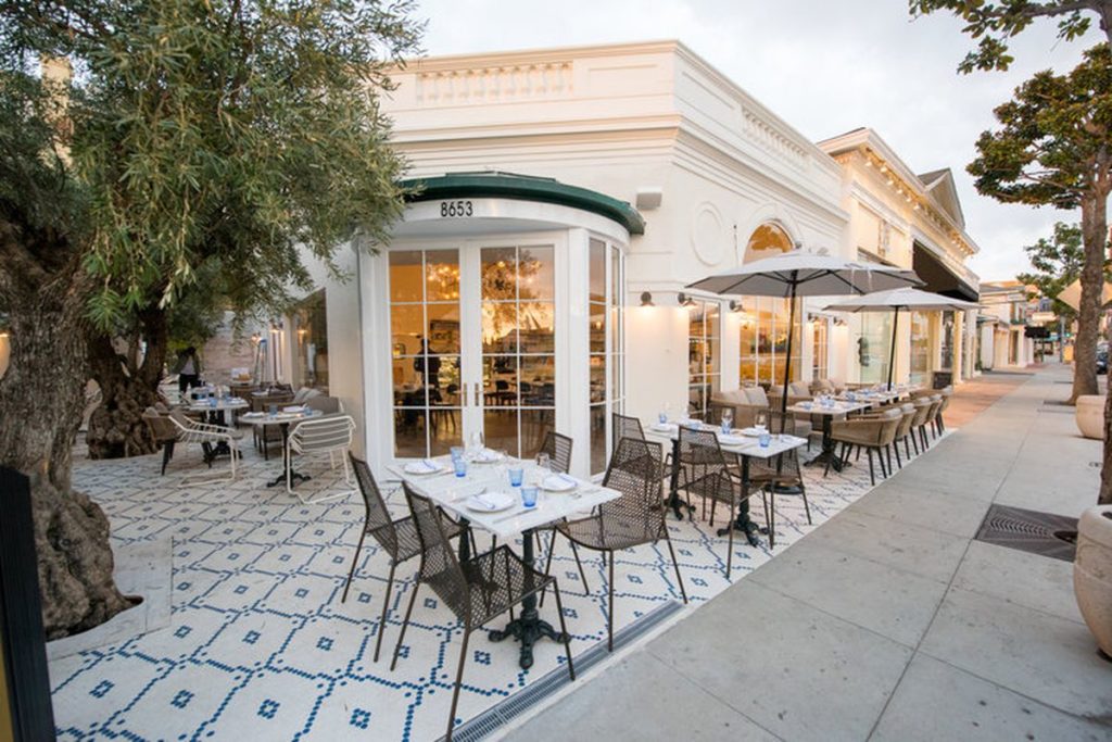 This image showcases an inviting outdoor patio area. The neatly arranged tables with place settings suggests a dining or entertainment space, while the well-maintained patio flooring adds to the aesthetic appeal. The surrounding building exterior hints at a high-end establishment.