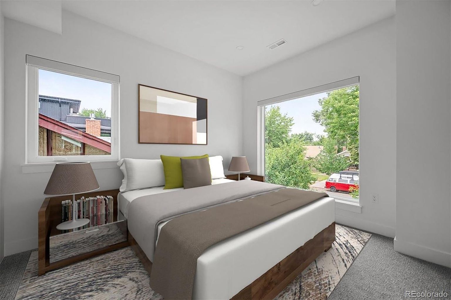 This is a bright and airy primary bedroom featuring two large windows that provide ample natural light. The room is decorated in neutral tones with a large bed, stylish side tables, and modern artwork. The overall impression is clean, comfortable, and inviting, perfect for relaxation.