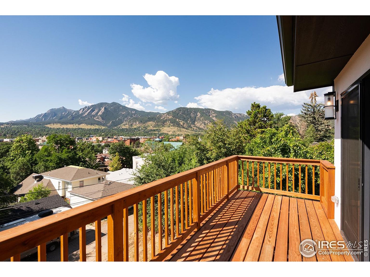 This image showcases a wooden deck with a railing, offering a scenic view of mountains and a town nestled among trees. The deck appears to be well-maintained, with a warm, natural wood finish. The view enhances the property's appeal, suggesting a relaxing outdoor space with a connection to nature.