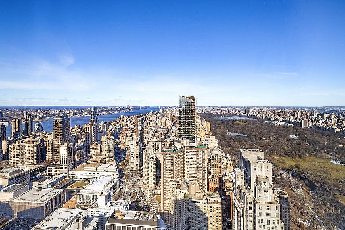 This high-altitude aerial view captures a breathtaking perspective of the New York City skyline, prominently featuring the expansive greenery of Central Park alongside dense urban architecture. The composition highlights the contrast between the natural landscape and the towering skyscrapers, including the iconic One57 building, under a clear blue sky. The perspective provides a grand, cinematic sense of scale, emphasizing the prime location and prestige of the surrounding real estate.
