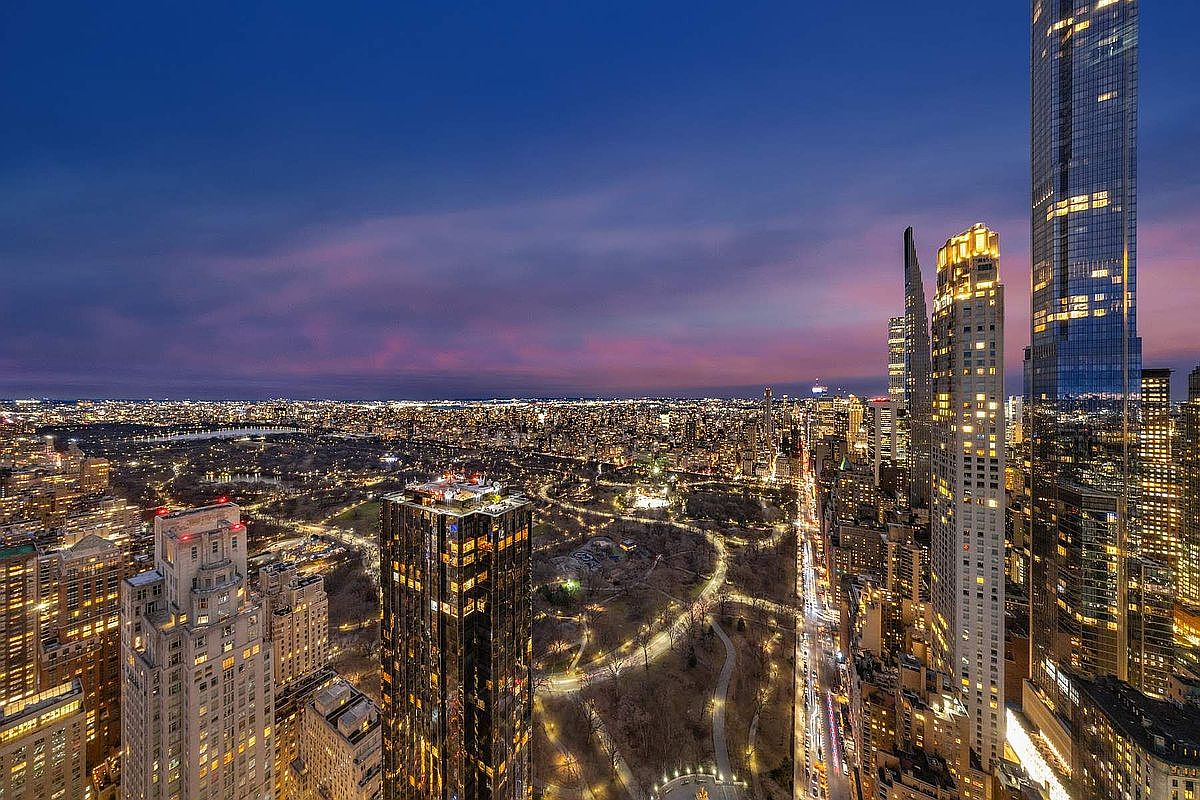 This stunning aerial view captures the iconic New York City skyline at dusk, showcasing the dramatic contrast between the illuminated skyscrapers and the dark expanse of Central Park. The perspective highlights the architectural grandeur of luxury high-rise towers, with the city's grid layout and winding park paths creating a sophisticated urban atmosphere. The deep blue and purple hues of the twilight sky provide a cinematic backdrop, emphasizing the prestige and prime location of the property.