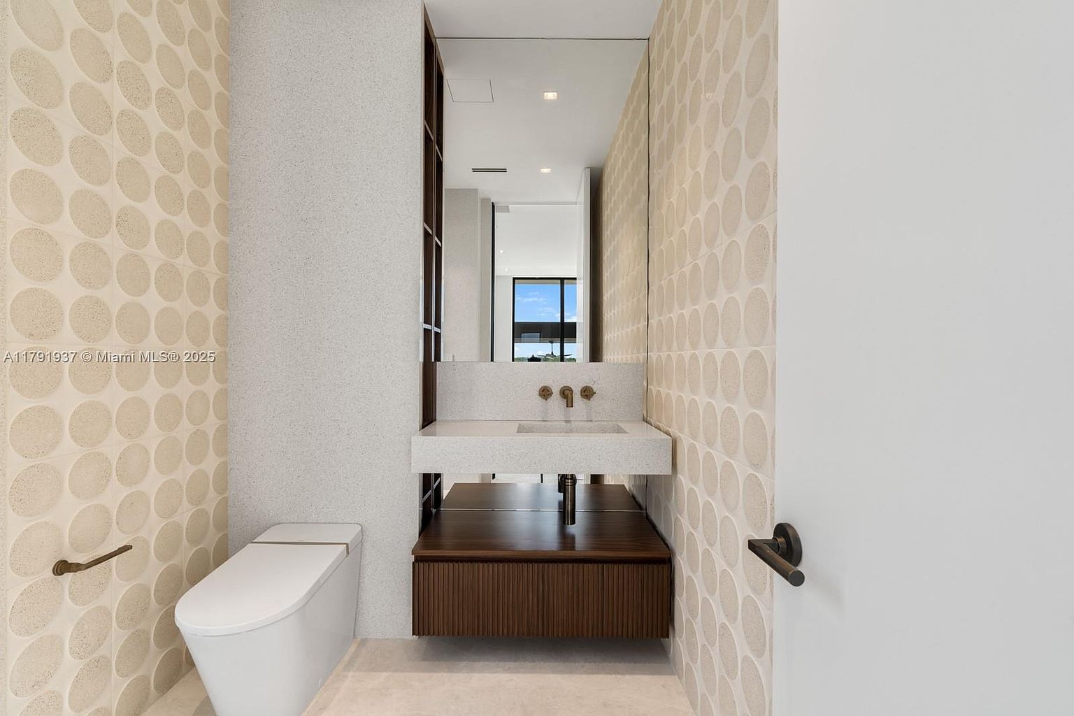 This is a modern guest bathroom featuring a wall-mounted toilet and a floating vanity with a dark wood cabinet. The walls are decorated with a unique circular pattern on one side and a speckled texture on the other. A large mirror hangs above the vanity, reflecting the light and creating a sense of spaciousness.