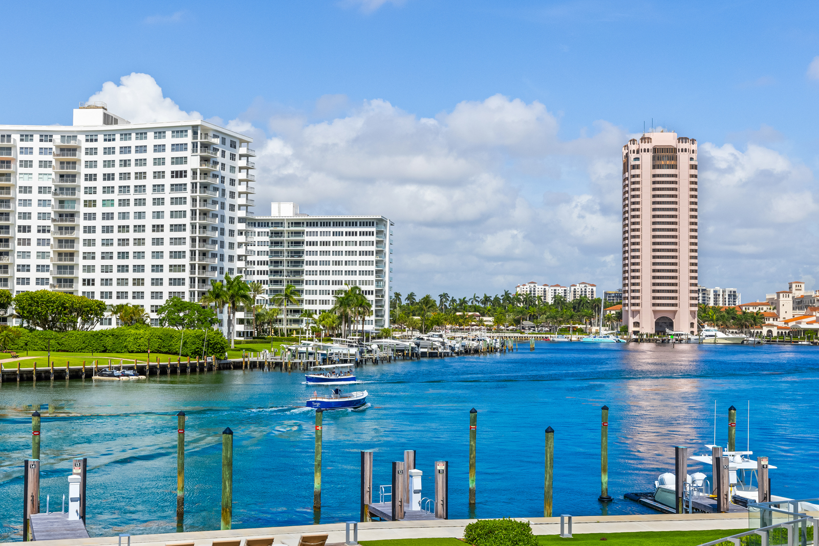 This stunning exterior shot showcases waterfront condos with a beautiful view of the waterway. The scene features a vibrant blue waterway with boats, docks, and lush green landscaping along the shore. The architecture of the condos is modern and elegant, creating an inviting and luxurious atmosphere.