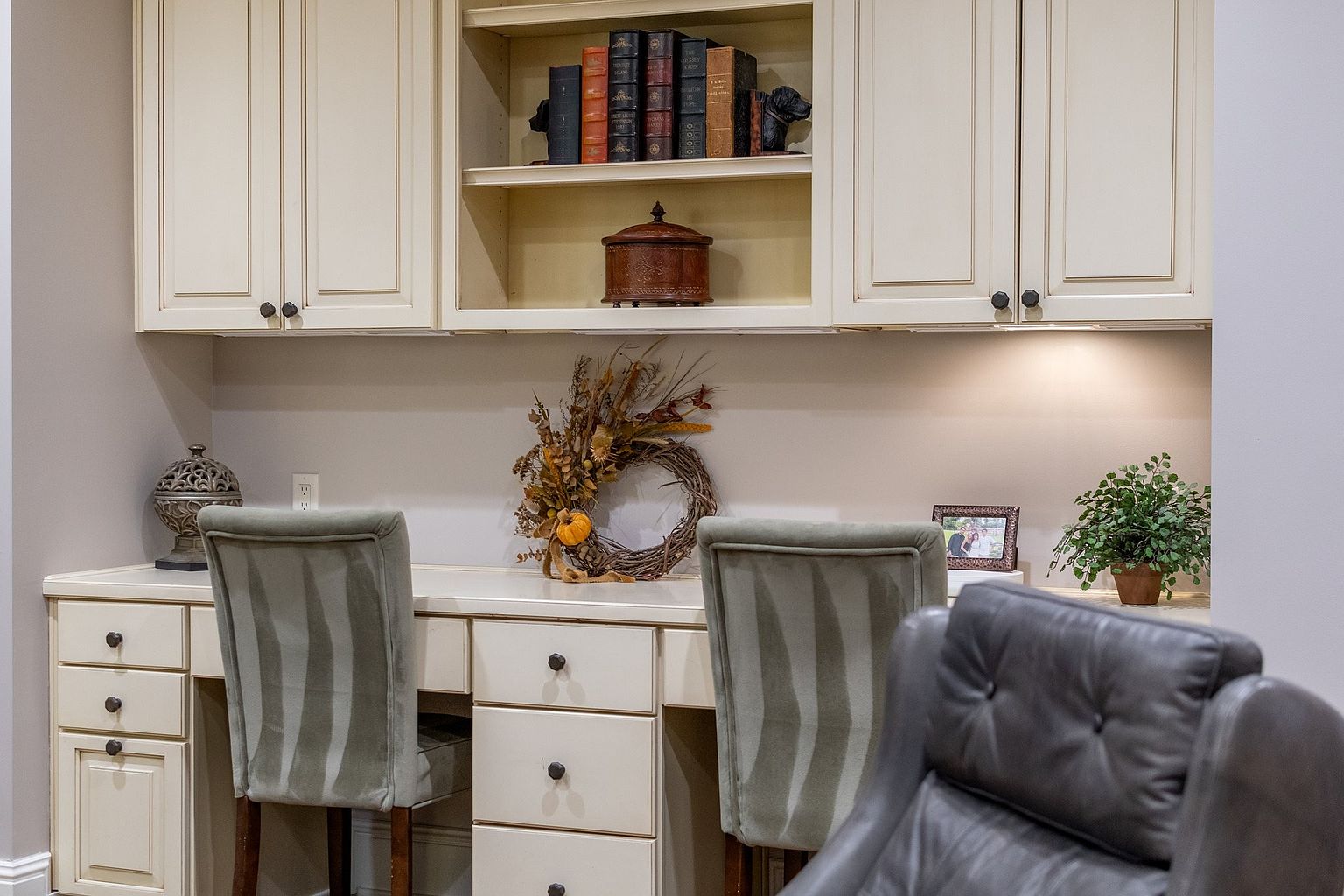 This interior shot showcases a well-organized home office space with built-in cabinetry and a desk area. The neutral color palette creates a calm and inviting atmosphere, complemented by decorative items and comfortable seating. The space is designed for productivity and aesthetic appeal, making it an ideal workspace.