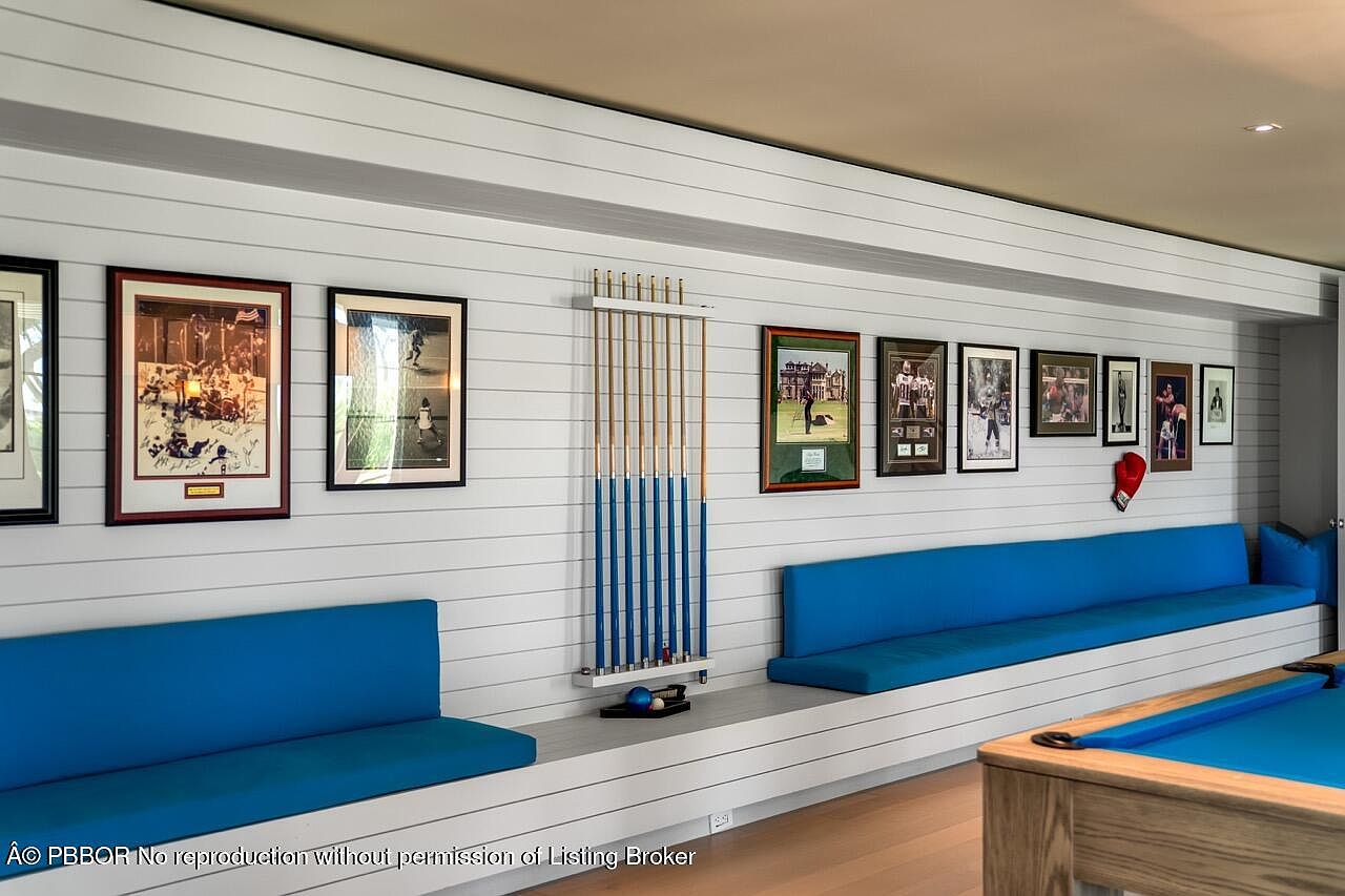 This interior shot showcases a recreational area with a pool table and built-in seating. The walls are adorned with framed artwork and sports memorabilia, adding character to the space. The blue cushions on the seating provide a pop of color against the neutral tones of the room, creating a comfortable and inviting atmosphere.