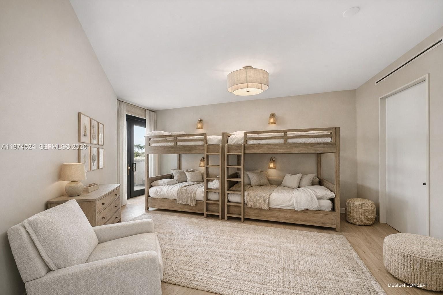 This bright and airy guest bedroom features two sets of light wood bunk beds, providing ample sleeping space with a clean, neutral aesthetic. A comfortable armchair sits in the foreground on a large textured rug, while a dresser with a lamp adds functional storage to the room. The space is finished with light-toned wood flooring and a glass door that leads to an outdoor area, creating a serene and inviting atmosphere.