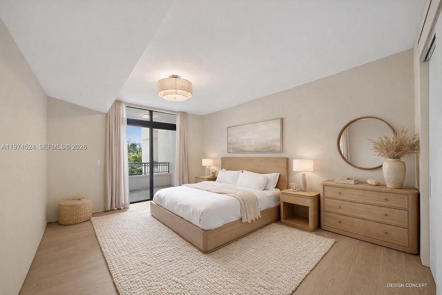 This serene primary bedroom features a neutral color palette with light wood flooring and a textured area rug. The room is anchored by a platform bed with a light wood headboard, flanked by matching nightstands and lamps, while a large dresser with a round mirror and decorative vase adds functional elegance. A sliding glass door provides access to a balcony, allowing natural light to fill the space.