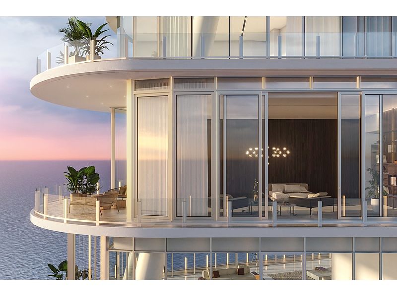 This image showcases the exterior of a modern high-rise building, focusing on the balconies. The balconies feature glass railings and outdoor furniture, offering stunning ocean views. The architecture is sleek and contemporary, emphasizing luxury living with seamless indoor-outdoor transitions.