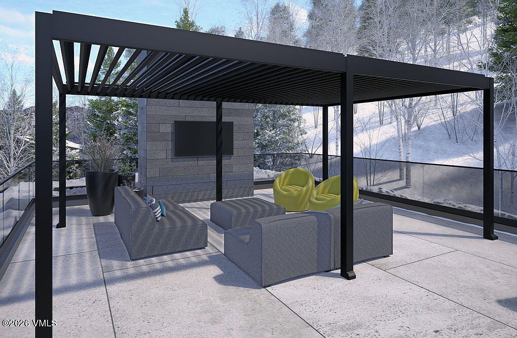 This image showcases a modern outdoor living space featuring a sleek, black pergola that provides partial shade. The patio is furnished with contemporary gray seating, including a sofa, ottoman, and armchairs, complemented by two vibrant green accent chairs. A stone-clad wall with a mounted television adds a touch of luxury, while the surrounding landscape offers a serene mountain view.