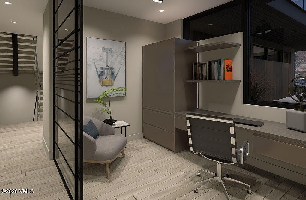 This is an interior shot of a modern office space featuring a built-in desk and shelving unit, a comfortable chair, and a framed artwork of a gondola. The room is well-lit, with a large window providing natural light, and the overall design is sleek and minimalist, creating a functional and stylish workspace. The perspective is from the doorway, looking into the office space.