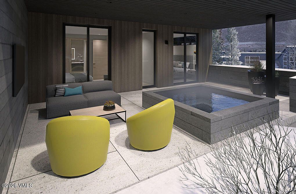 This image showcases a modern patio or balcony area, featuring a gray sofa with blue pillows, two yellow chairs, and a small coffee table. A hot tub is integrated into the design, and large windows offer views into the interior spaces. The overall aesthetic is contemporary and luxurious, perfect for relaxation and entertaining.