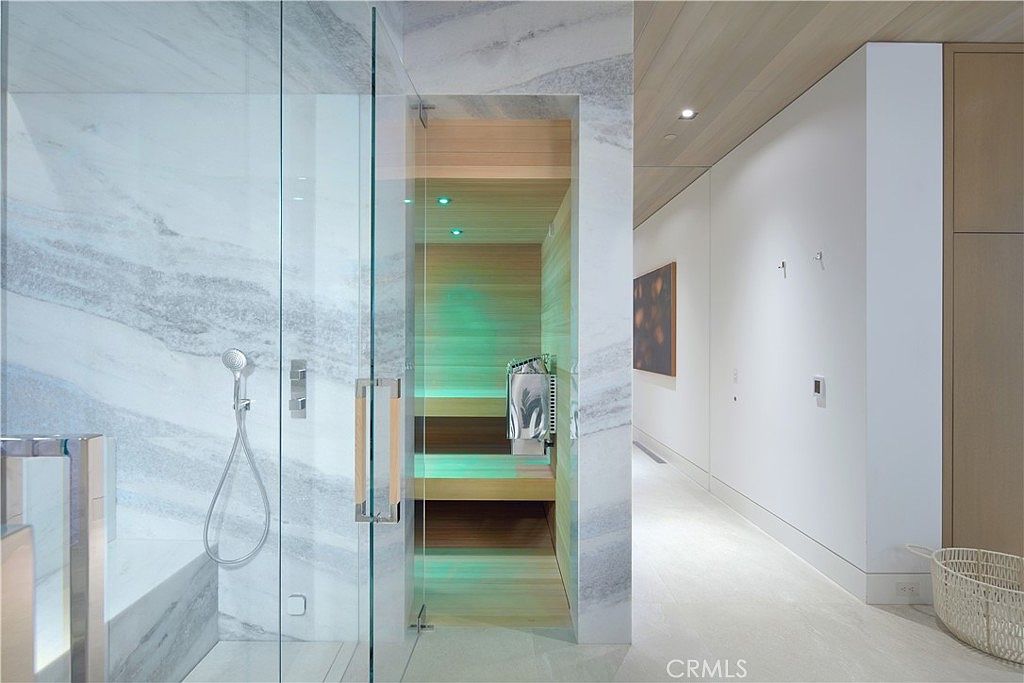 This luxurious bathroom features a glass-enclosed shower with light-toned stone walls and a built-in sauna with warm wood paneling and ambient green lighting. The space transitions into a bright, minimalist hallway with light wood ceiling accents and a woven basket in the corner. The overall aesthetic is modern, spa-like, and sophisticated, emphasizing high-end materials and clean lines.