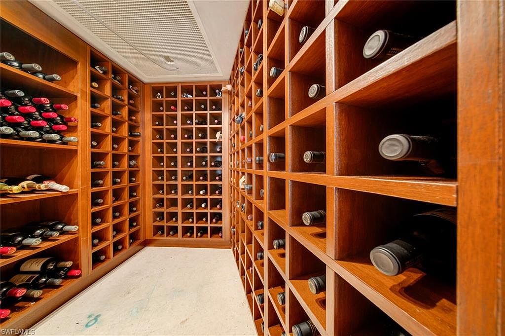 This image showcases a well-stocked wine cellar with custom wooden shelving. The shelves are filled with numerous wine bottles, creating a visually appealing display. The room is designed to store and showcase a wine collection, adding a touch of luxury to the property.