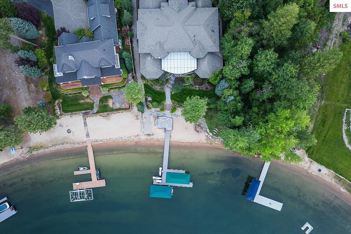 This aerial view showcases a luxurious waterfront property with multiple docks and boat slips. The homes feature well-manicured lawns, mature trees, and direct access to the water. The perspective highlights the property's prime location and upscale amenities, emphasizing its appeal for waterfront living.