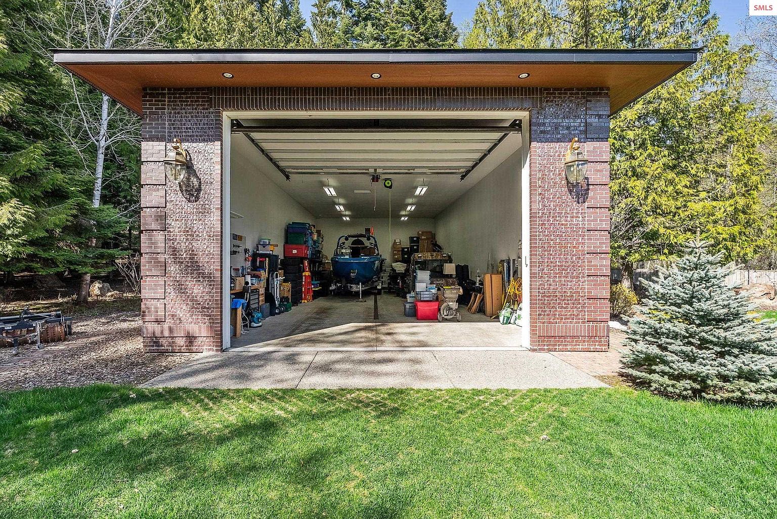 This image showcases a well-organized garage with a boat inside, suggesting ample space for vehicles and storage. The garage features a brick exterior with stylish lighting fixtures, adding to its curb appeal. The well-maintained lawn in front enhances the overall presentation, making it an attractive feature for potential buyers.