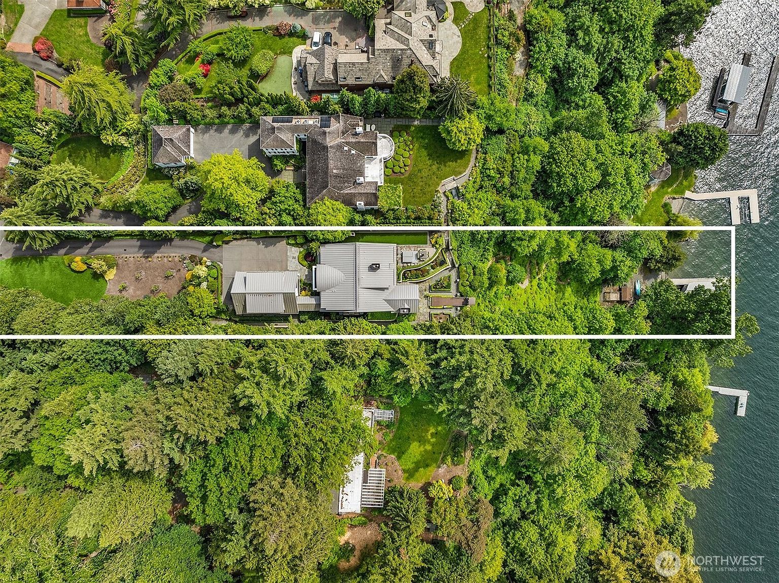 This high-altitude aerial view captures a luxurious waterfront estate nestled within a lush, densely wooded landscape. The property features a modern residence with a distinctive metal roof, expansive manicured lawns, and a private dock extending into the adjacent lake. The perspective highlights the property's secluded, park-like setting and its seamless integration with the natural environment.