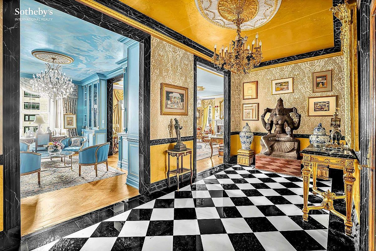 This opulent hallway features a striking black and white checkered floor, ornate gold detailing, and a decorative statue. The hallway connects to multiple rooms, showcasing a luxurious and well-designed interior. The perspective is from the entrance, looking into the hallway and beyond.