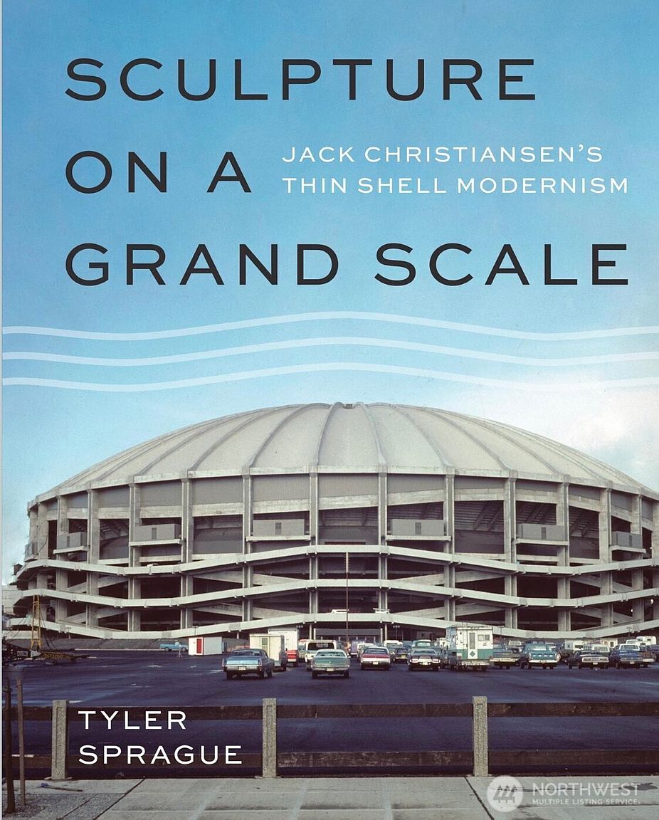 The image showcases the front view of a large, domed stadium with a unique architectural design, possibly a sports arena or event center. Several vintage cars are parked in the foreground, adding a retro feel to the scene. The building's facade features a distinctive pattern of horizontal lines and concrete supports, creating a visually striking and monumental impression.