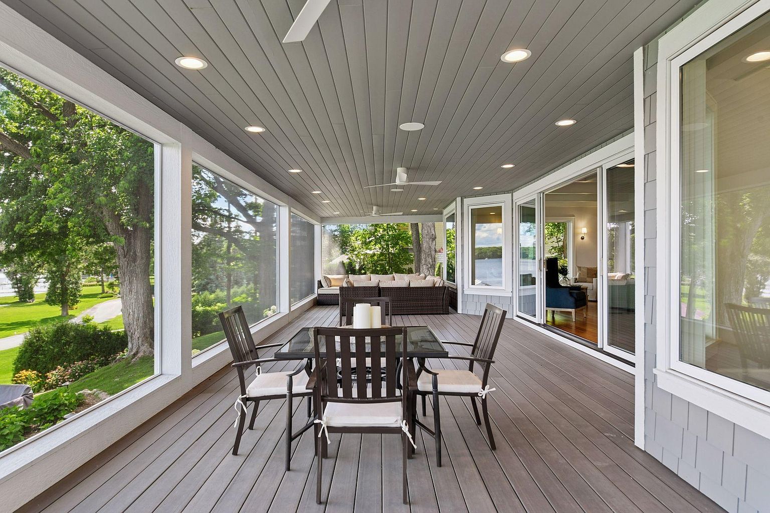 This image showcases a spacious and inviting outdoor patio or deck area. The space is furnished with a dining table and chairs, suggesting an ideal spot for outdoor meals and gatherings. Large windows and sliding glass doors provide ample natural light and seamless indoor-outdoor flow, enhancing the appeal of this outdoor living space.