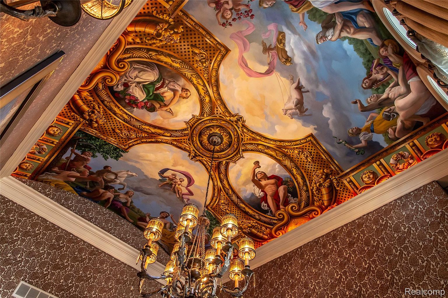 The image showcases an ornate ceiling mural, likely within a high-end residence. The mural features classical figures and intricate gold detailing, creating a luxurious and artistic focal point. The perspective is from below, emphasizing the grandeur and craftsmanship of the ceiling design.