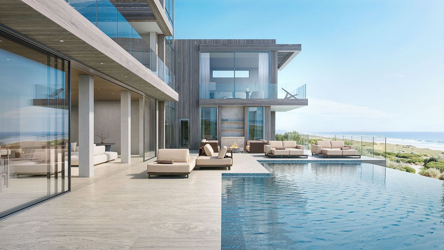 This luxurious coastal residence features a seamless indoor-outdoor flow, highlighted by an expansive infinity-edge pool that overlooks the ocean. The patio is finished with large-format stone tiles and furnished with contemporary lounge seating, while the home itself showcases modern architecture with light wood siding and extensive glass walls. A cozy outdoor fire feature adds a warm focal point to the terrace, creating an inviting atmosphere for relaxation against a backdrop of dunes and sea.