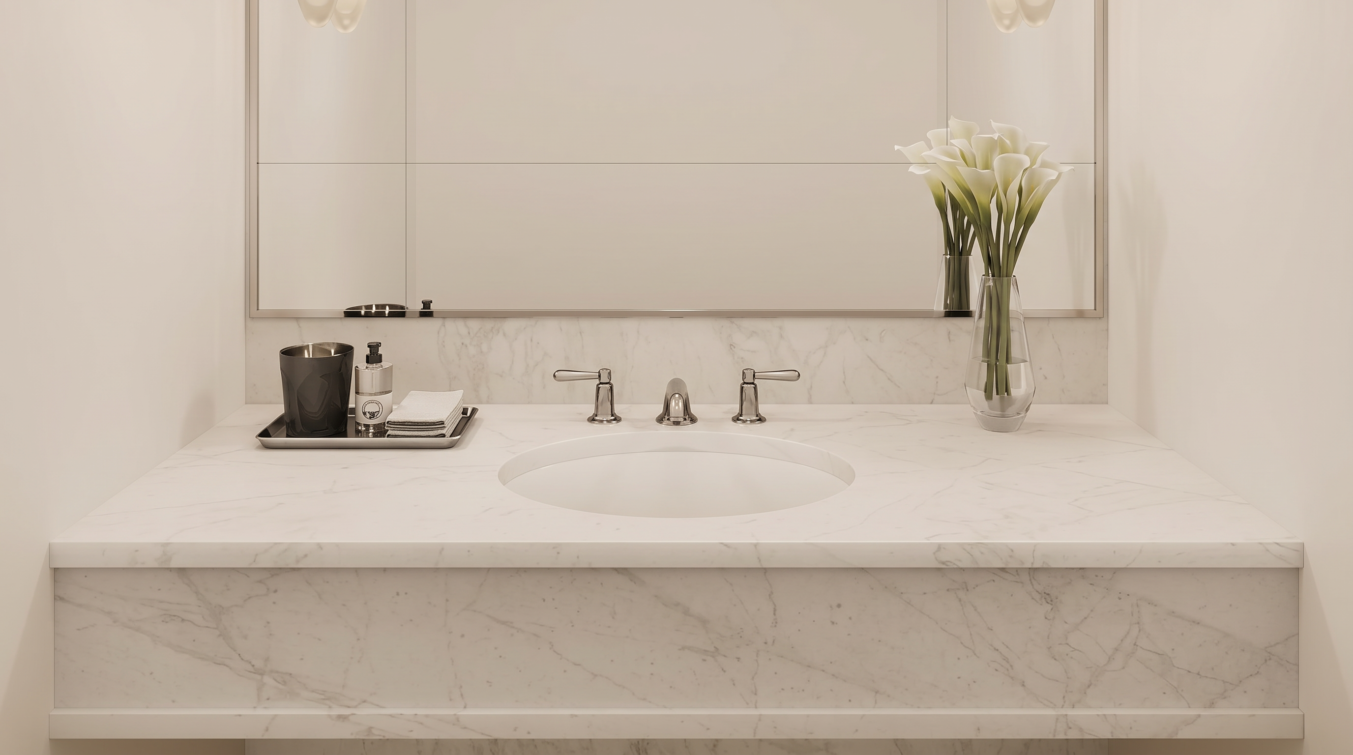 This elegant powder room features a floating marble vanity with a clean, minimalist aesthetic and polished chrome fixtures. A large, frameless mirror reflects the soft glow of two contemporary wall sconces, while a delicate vase of calla lilies adds a touch of organic sophistication. The space is grounded by light-toned herringbone wood flooring, creating a serene and high-end atmosphere.