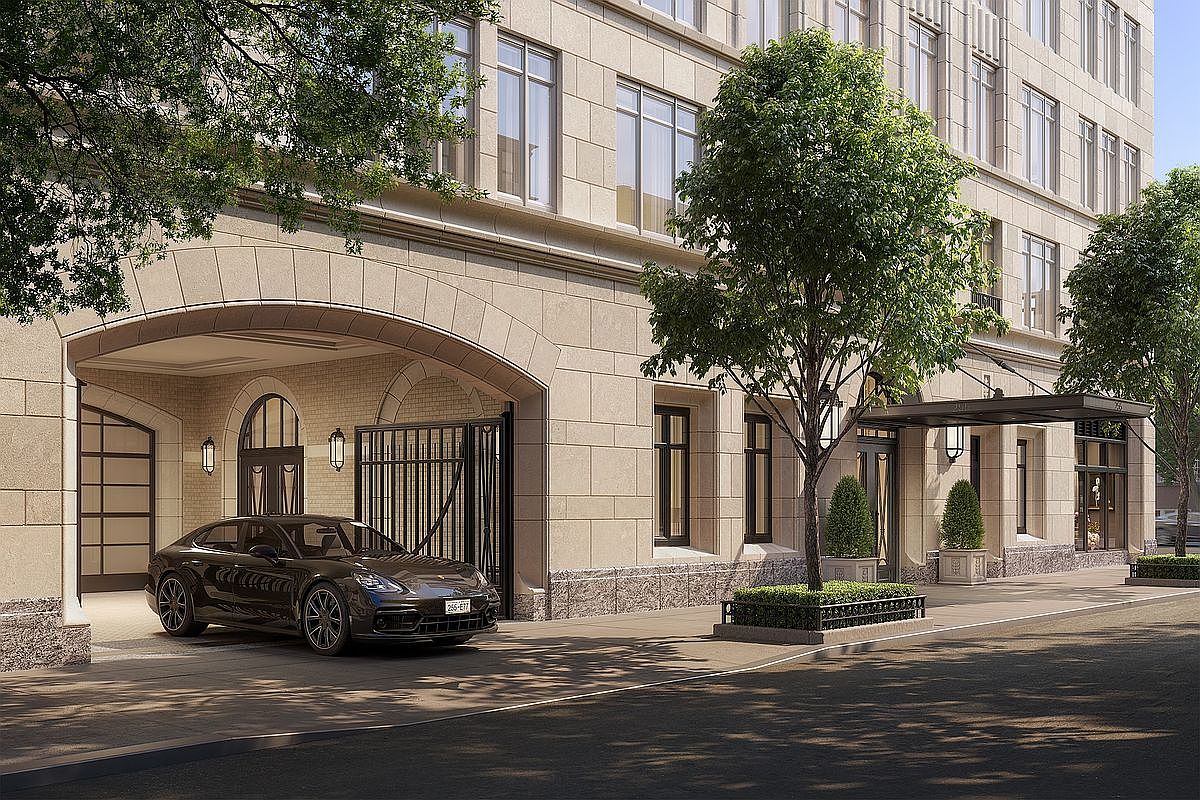 This sophisticated exterior view captures the grand, stone-clad entryway of a luxury residential building, featuring a classic arched porte-cochère and a sleek black sedan parked underneath. The scene is framed by mature trees and elegant architectural detailing, conveying an atmosphere of exclusivity and refined urban living. The perspective is a low-angle, eye-level shot that emphasizes the building's impressive scale and high-end aesthetic.