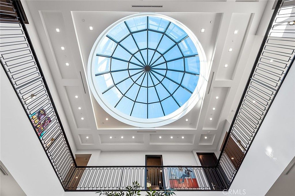 This image showcases a stunning architectural detail: a large, circular skylight set into a multi-tiered ceiling. The skylight allows natural light to flood the interior space, creating a bright and airy atmosphere. The surrounding ceiling features recessed lighting and decorative panels, adding to the overall elegance and sophistication of the design.