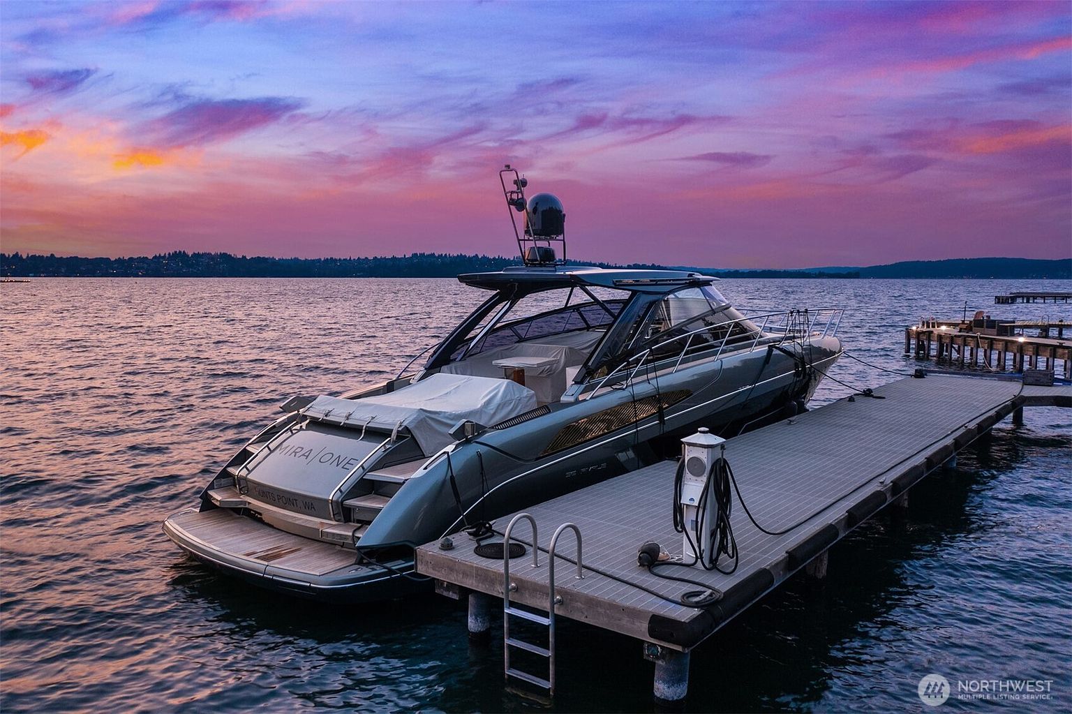 The image showcases a modern yacht docked at a pier during a vibrant sunset. The yacht, featuring sleek lines and a covered seating area, is moored alongside a well-maintained pier equipped with a fueling station. The sky is painted with hues of pink, purple, and orange, reflecting on the calm water, creating a serene and luxurious atmosphere.