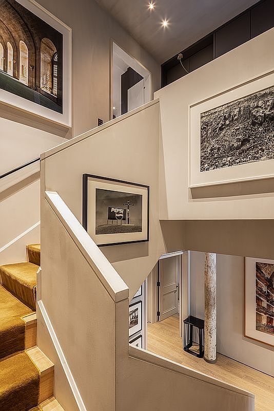 This interior shot showcases a stylish hallway and staircase area. The staircase is carpeted with a warm-toned runner, and the walls are adorned with framed artwork, adding a touch of sophistication. The space features neutral tones and modern architectural details, creating an inviting and visually appealing transition between levels.