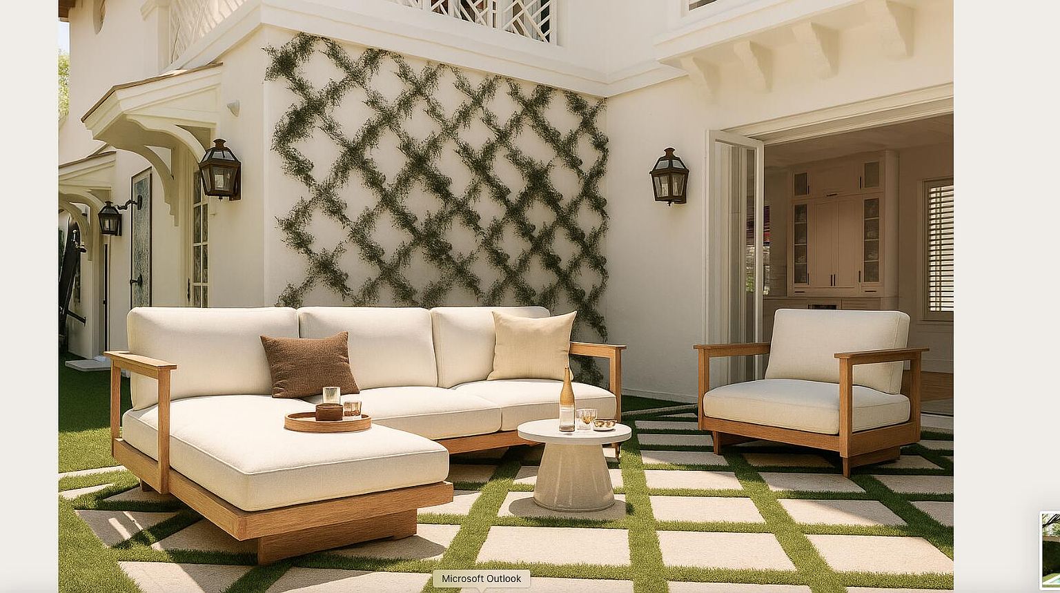 This image showcases a stylish outdoor patio area, featuring a comfortable white cushioned sofa and armchair set with wooden frames, arranged on a unique stone-tiled surface interspersed with grass. The backdrop includes a white wall adorned with climbing vines in a diamond pattern and elegant outdoor lanterns, creating a serene and inviting atmosphere perfect for relaxation and entertaining. The patio seamlessly connects to the interior through large glass doors, enhancing the indoor-outdoor living experience.