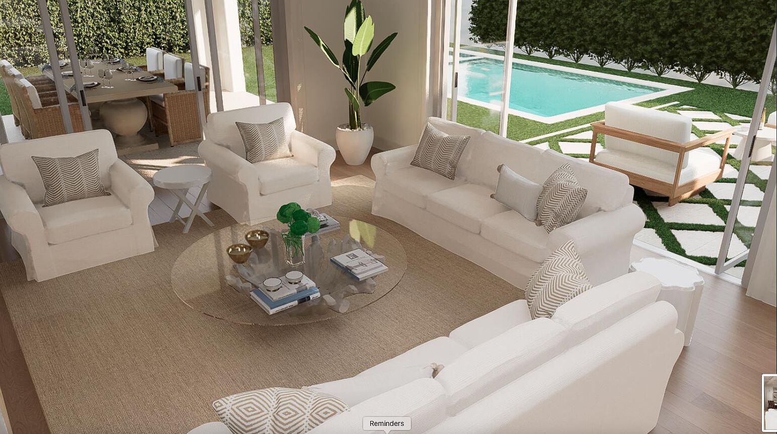 This is an interior shot of a sun-drenched living room featuring white sofas and armchairs arranged around a glass coffee table on a neutral rug. The room is open to an outdoor patio and pool area through large glass doors, creating a seamless indoor-outdoor living experience. The style is modern and airy, emphasizing natural light and comfortable elegance.