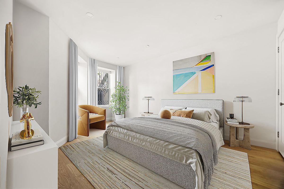 This is a bright and airy primary bedroom featuring a neutral color palette. The room includes a large bed with a patterned throw, a side table with a lamp, and an abstract painting above the bed. A window with sheer curtains provides natural light, and a comfortable chair sits near the window.