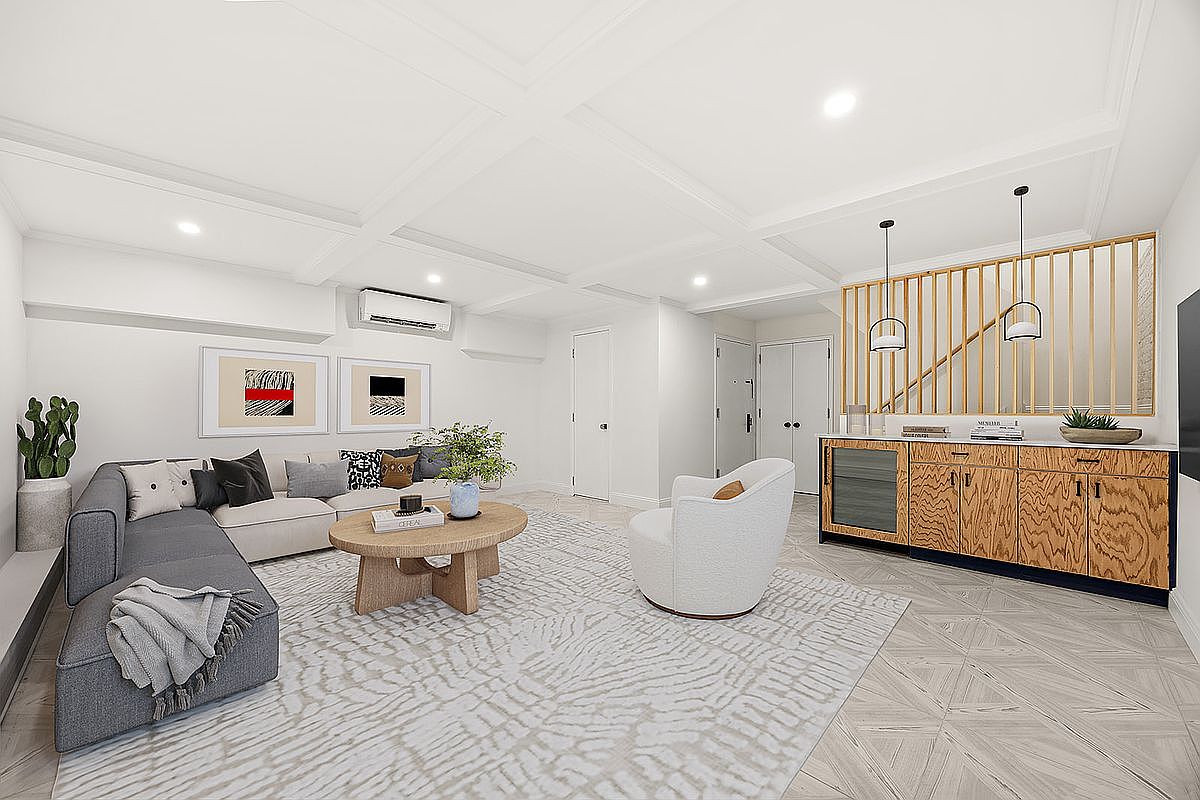 This is a bright and airy living room featuring a modern sectional sofa, a round coffee table, and a stylish accent chair. The room is decorated with contemporary artwork and has a built-in bar area with wooden cabinetry and pendant lighting. The overall impression is clean, comfortable, and inviting, perfect for relaxation and entertaining.