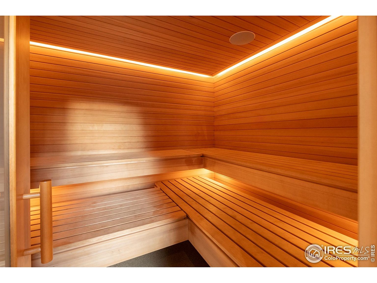 This image showcases a well-lit, wood-paneled sauna. The sauna features tiered wooden benches, creating a relaxing and inviting atmosphere. The warm lighting enhances the natural wood tones, suggesting a luxurious and health-focused amenity.