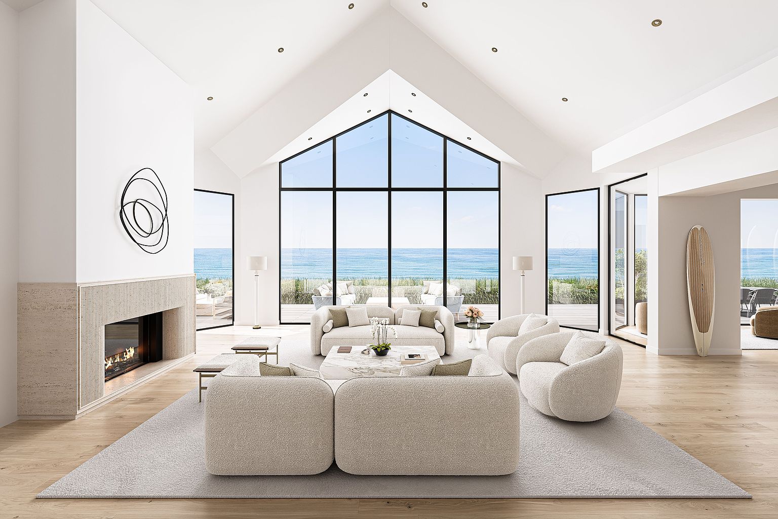 This is a bright and airy living room with a modern coastal design. The room features a high vaulted ceiling, large windows with ocean views, and neutral-toned furniture including a sectional sofa and armchairs. A fireplace and abstract art add focal points, while the light wood flooring and area rug contribute to the room's serene and inviting atmosphere.