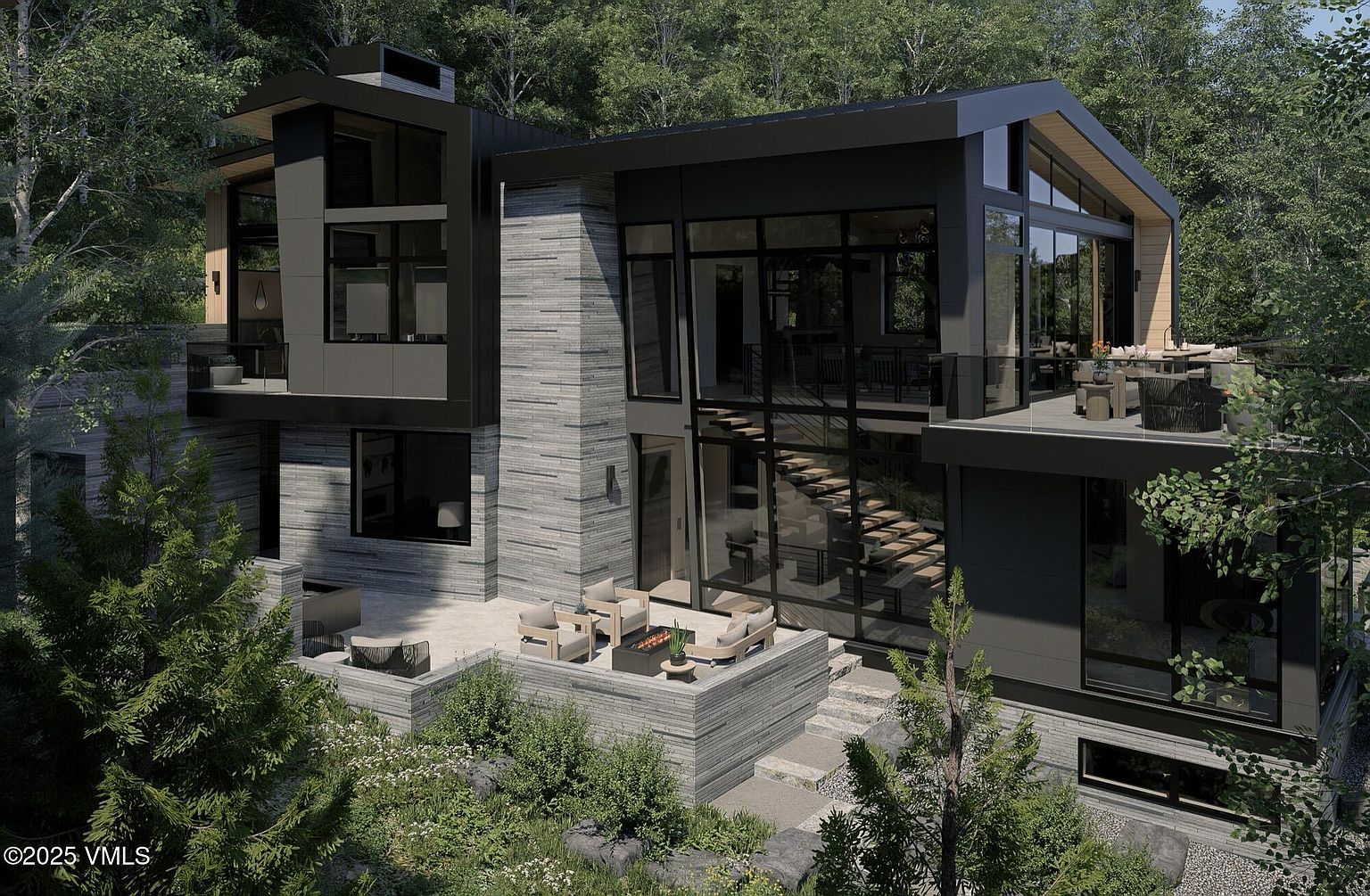 This image showcases the rear exterior of a modern, multi-level home nestled among lush trees. The architectural design features a combination of stone and dark metal cladding, large windows, and multiple outdoor living spaces, including a patio with seating and a deck accessible by an exterior staircase. The overall impression is one of sophisticated design integrated seamlessly with the natural landscape.