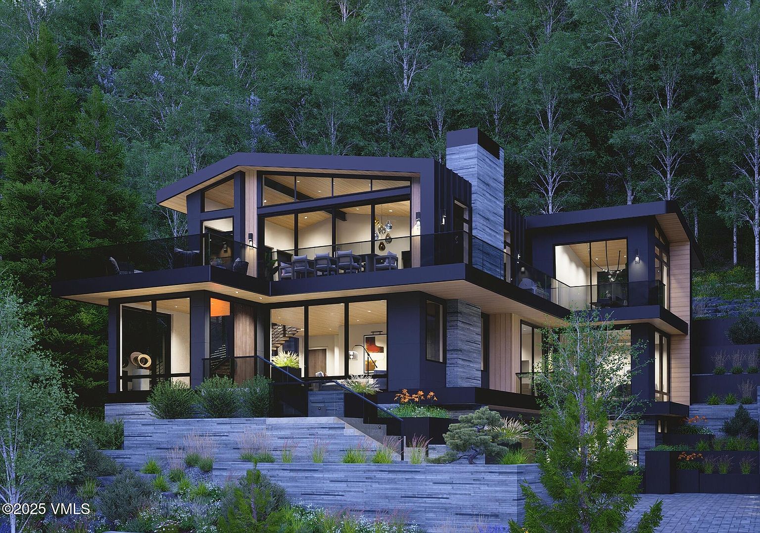 This is a stunning front exterior view of a modern, multi-level home nestled in a wooded area. The house features a combination of dark siding, wood accents, and large glass windows, creating a sleek and contemporary aesthetic. The landscaping includes tiered stone walls and lush greenery, enhancing the property's curb appeal and blending it seamlessly with its natural surroundings.