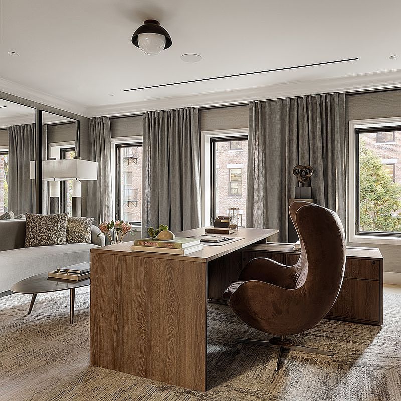 This sophisticated home office features a sleek, modern wooden desk paired with a distinctive brown, mid-century modern egg chair. The room is elegantly appointed with floor-to-ceiling grey curtains, a plush textured rug, and a comfortable sofa in the background, creating a professional yet inviting atmosphere. The perspective is a wide-angle shot that captures the harmonious blend of contemporary furniture and refined architectural details.