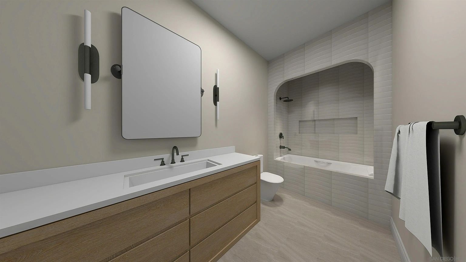 This is a primary bathroom featuring a modern vanity with a white countertop and light wood drawers. A large rectangular mirror hangs above the sink, flanked by contemporary sconces. The bathroom includes a bathtub and shower area enclosed by light gray subway tiles, creating a clean and spa-like atmosphere. The perspective is from the doorway, showcasing the entire space.
