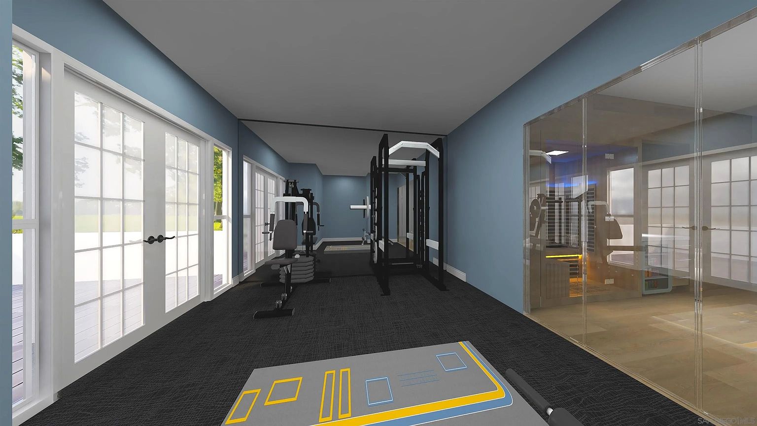 This is an interior shot of a home gym, featuring various exercise machines and equipment. The room has a blue wall color and dark carpeting, with large windows and glass doors providing natural light. A workout mat is visible in the foreground, suggesting a dedicated space for floor exercises.