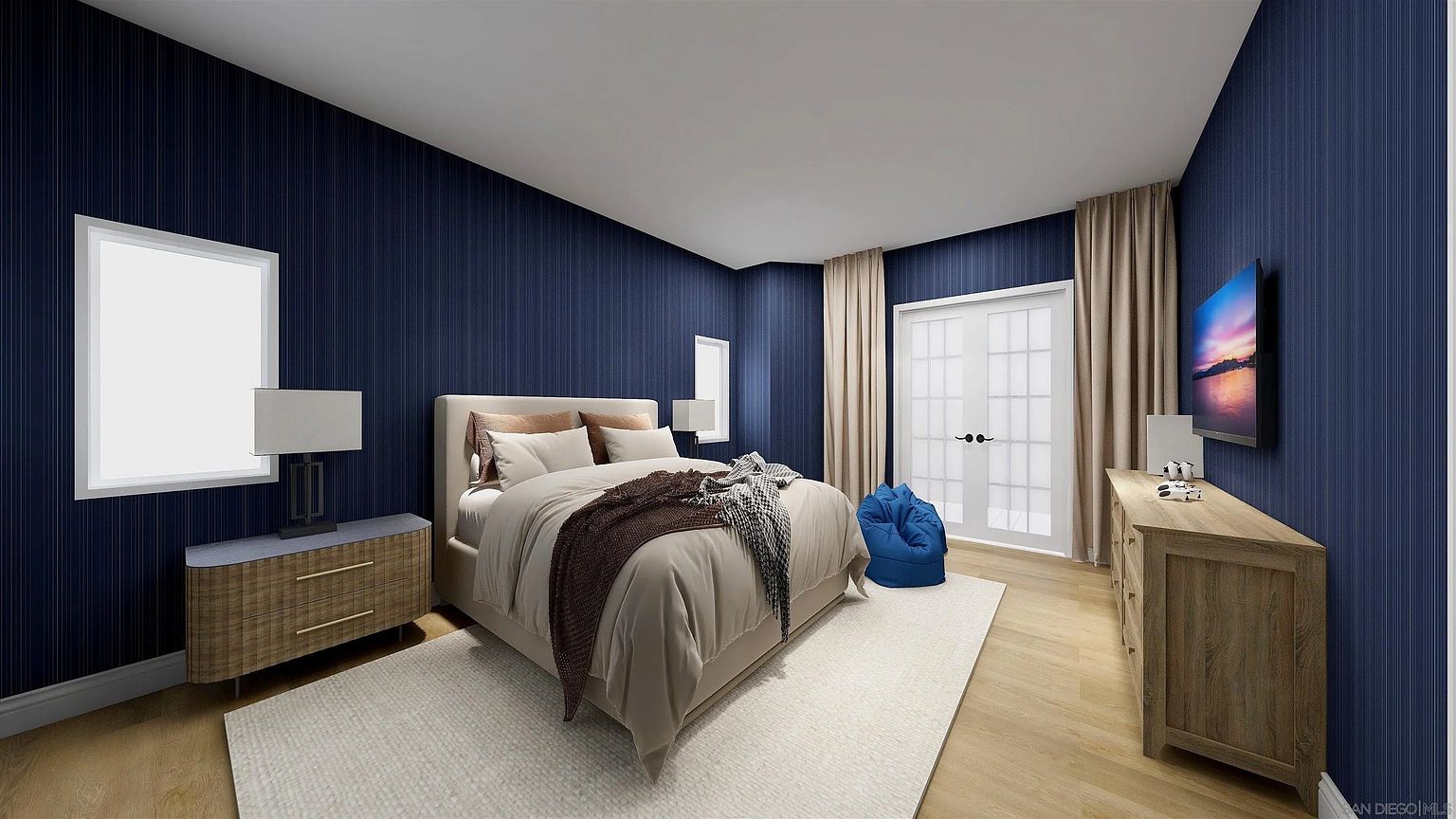 This is a primary bedroom featuring a queen-sized bed with neutral bedding and decorative pillows. The walls are a dark blue with vertical stripes, complemented by light wood flooring and a white area rug. A wooden dresser sits to the side of the bed, and a flat-screen TV is mounted on the wall. The room has a modern and cozy feel.