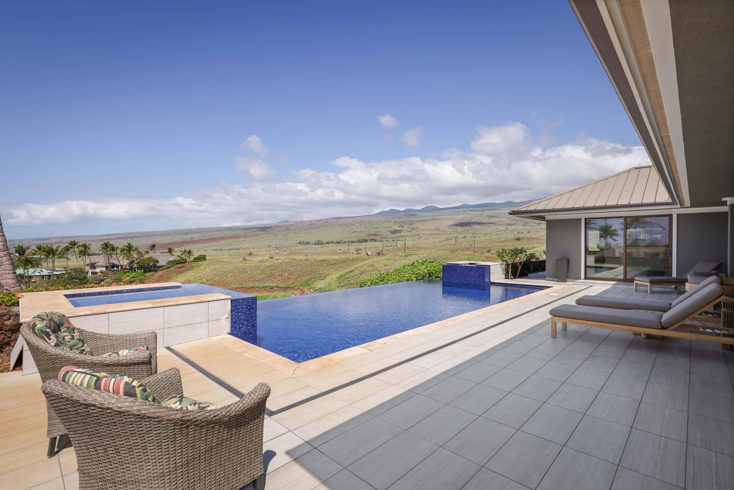 This image showcases a luxurious outdoor pool and patio area, perfect for relaxation and entertainment. The infinity pool blends seamlessly with the expansive landscape view, creating a serene and visually stunning effect. Comfortable lounge chairs and stylish outdoor furniture enhance the appeal of this high-end property.