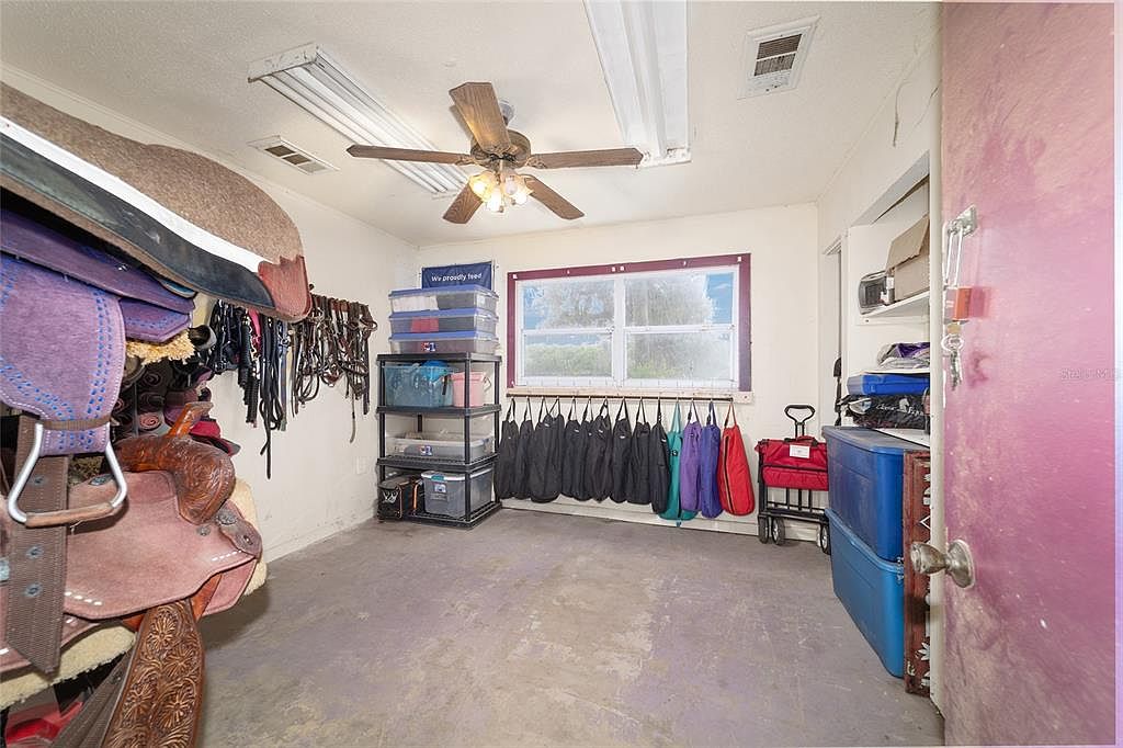 This is an interior shot of what appears to be a tack room or storage area, possibly in a barn or stable. The room is filled with horse-related equipment, including saddles, bridles, and storage containers. The space is functional and organized, with items neatly arranged for easy access.