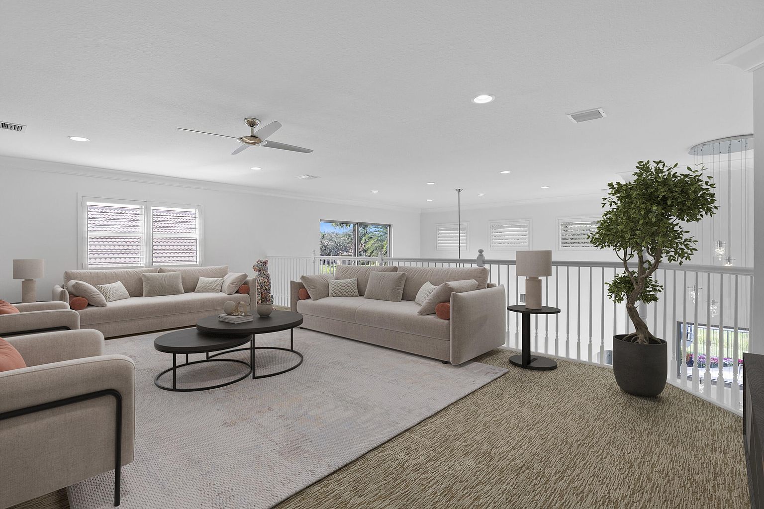 This is an interior shot of a spacious living room featuring two large sofas, a round coffee table, and an armchair. The room is bright and airy, with white walls and a neutral-toned rug. A large potted plant adds a touch of nature to the space, and the overall impression is one of comfort and elegance.