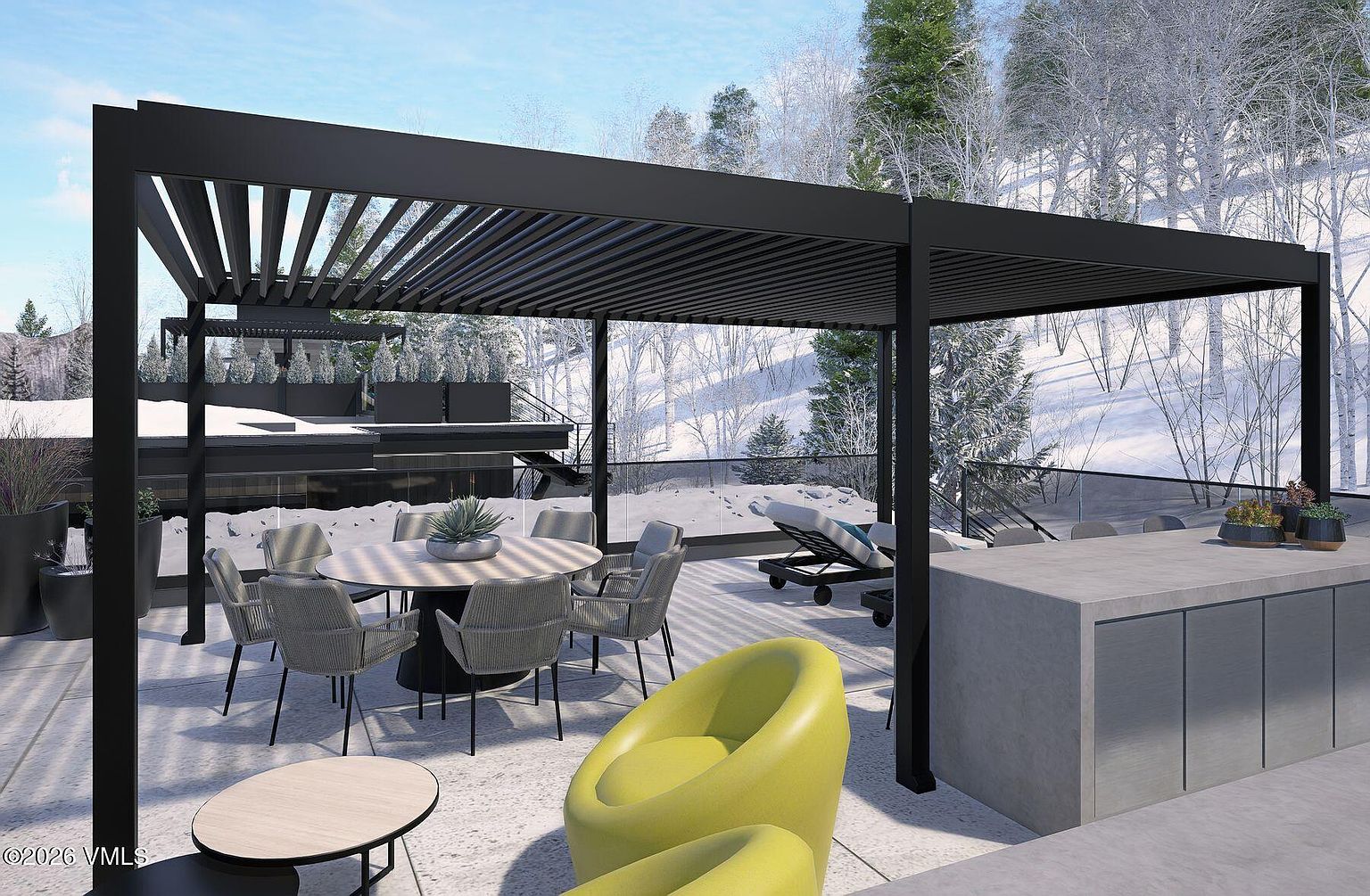 This modern outdoor terrace features a sleek black louvered pergola covering a dining area with a round table and woven chairs. To the right, a concrete outdoor kitchen island provides a functional prep space, while a vibrant lime-green lounge chair sits in the foreground. The setting overlooks a snowy, forested landscape, creating a striking contrast between the contemporary architectural design and the winter environment.